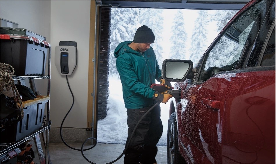 Man inside a garage plugging in an F150 Lightning to charge.