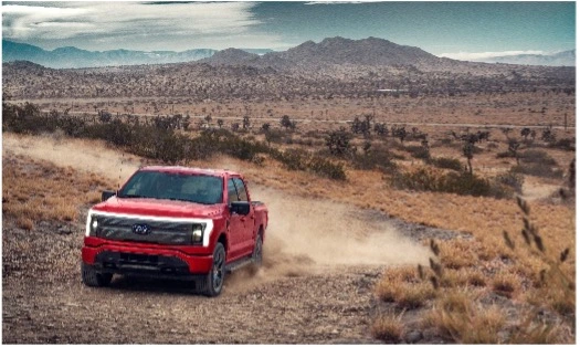 F150 Lightning driving down a dirt road.